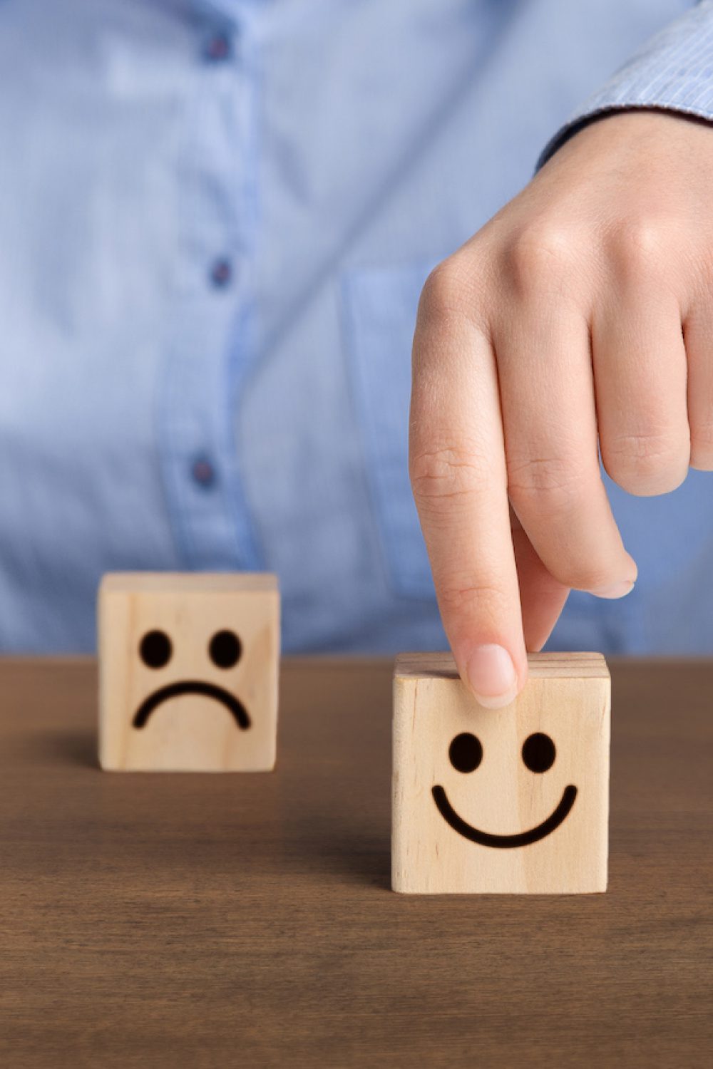 Hand of a businessman chooses a smiley face on wood block cube The best excellent business services rating. Hand of a businessman chooses a smiley face on wood block cube, panorama, copy space